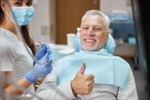 dental emergency in sutton belmont patient man sitting in dentist chair with dentist happy and thumbs up