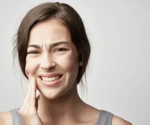 dental emergencies in belmont sutton woman with white teeth in tooth pain holding face with hands