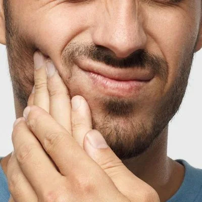 dental emergencies in belmont sutton man with tooth pain holding face with hands